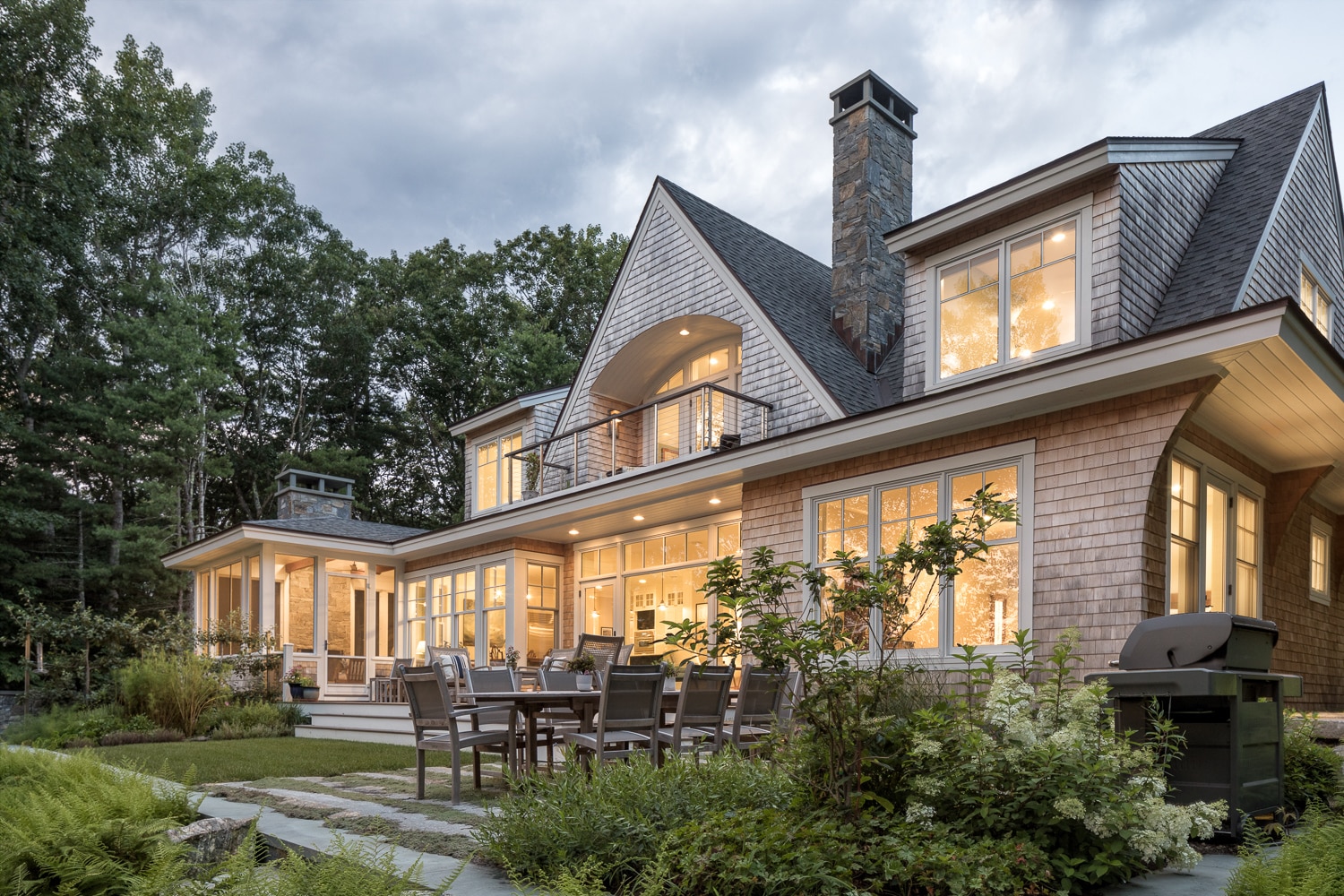 Surrounded by nature this is a classic New England cedar shake style house with a twist. A lot of outside living areas are integrated into the landscape surrounding the family home.