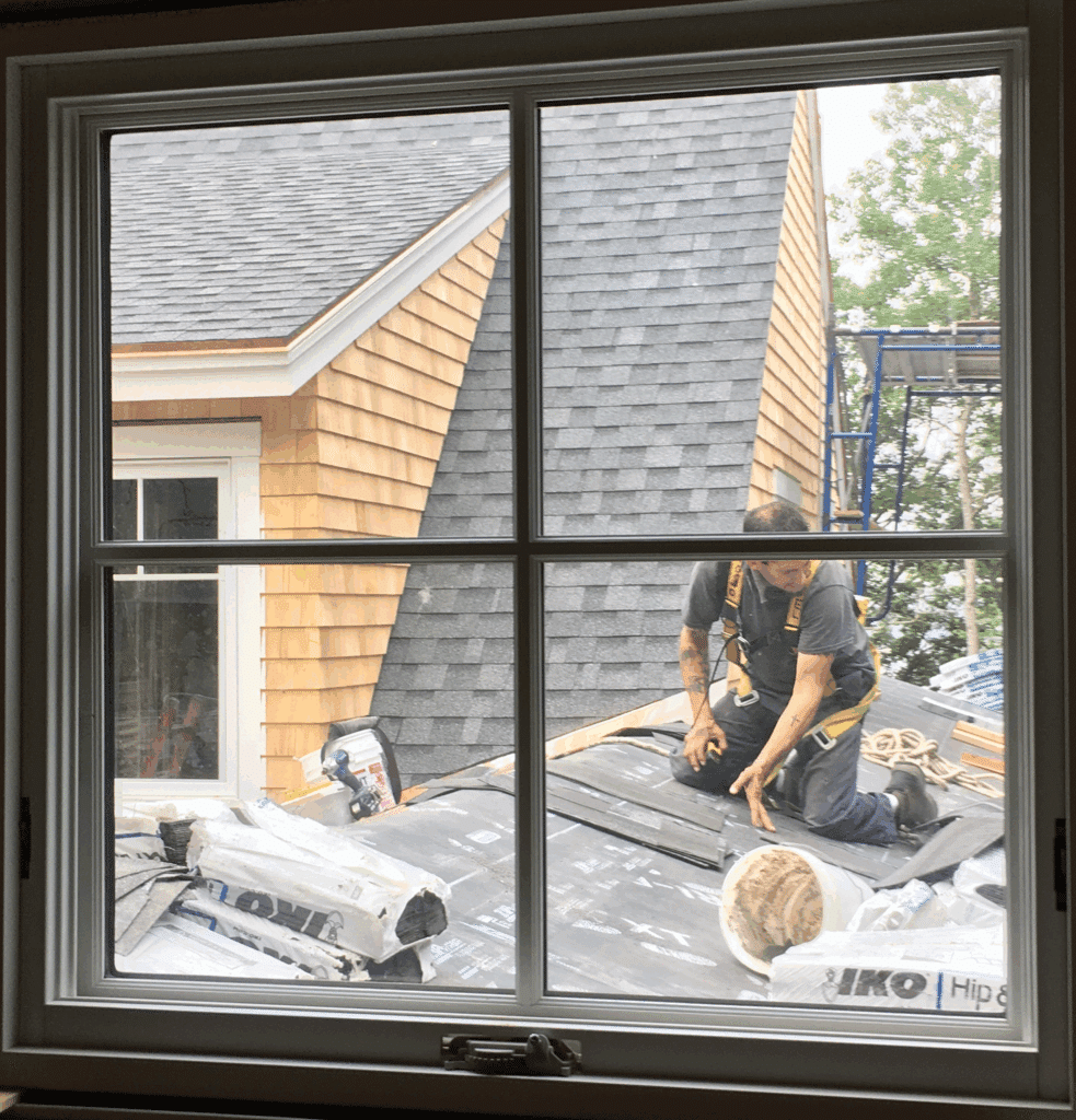 Looking through the window at worker roofing