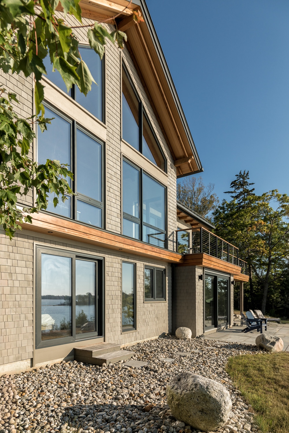 The huge windows and the combination of stained shingles and accented wood trim call attention to the detail and craftmanship that went into this custom house on the coast of Maine bult by Warren Construction Group.