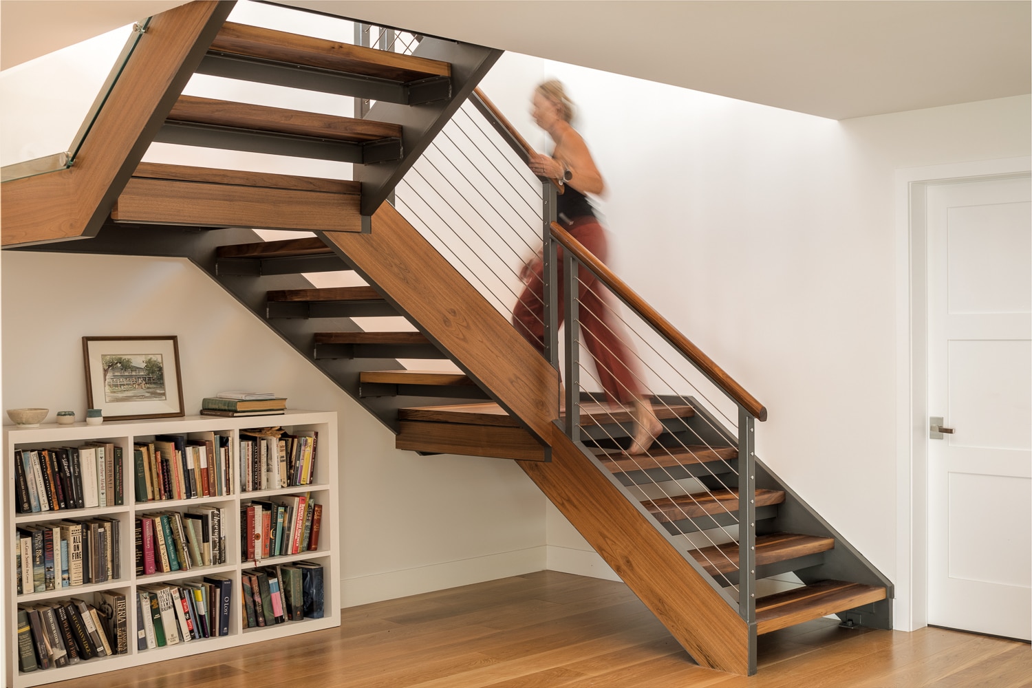 Modern floating staircase with hardwood treads, steel stringers, cable railing, in a luxury custom home built by Warren Construction Group.