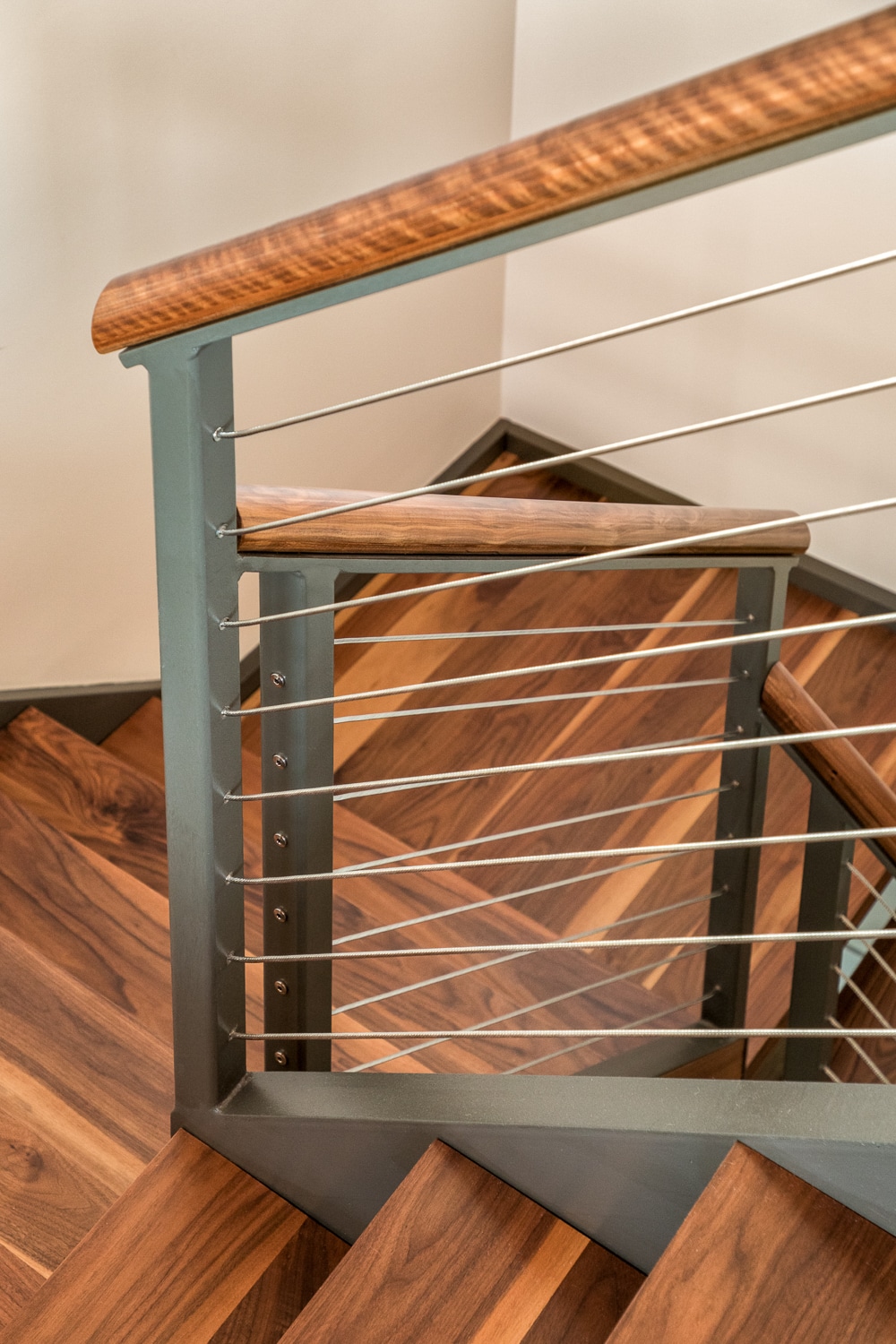 Custom hardwood staircase with cable railing system, steel balusters, and handrail in a luxury Maine home built by Warren Construction Group.