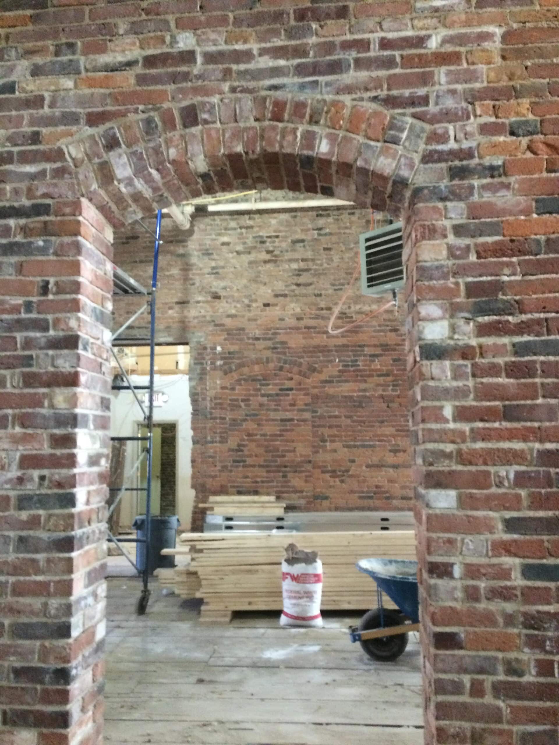 Restored historic brick archway and exposed masonry walls during commercial building renovation in Maine by Warren Construction Group.