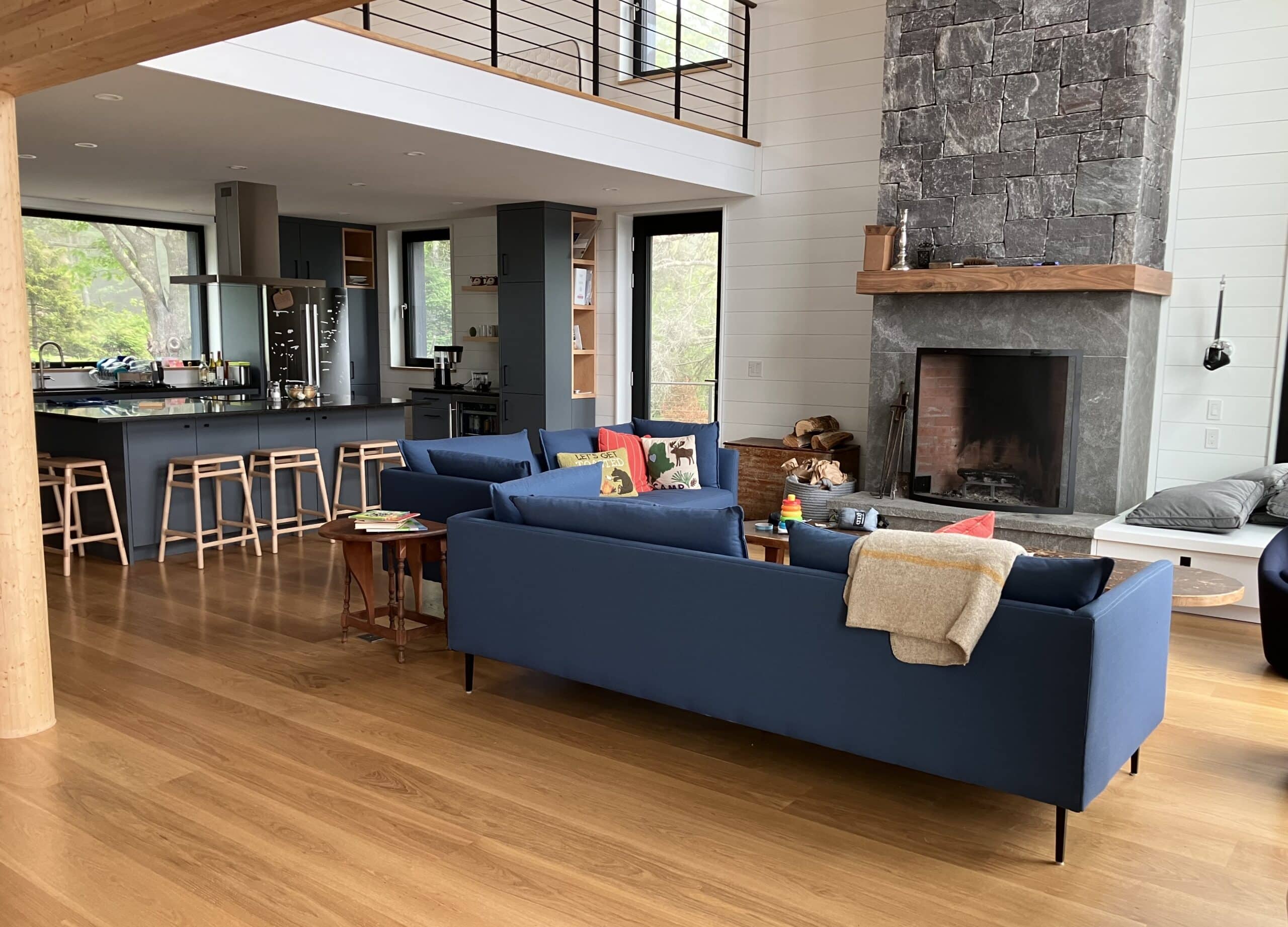 Stone fireplace and kitchen. The expansive living area in this custom panelized house on the coast of Maine
