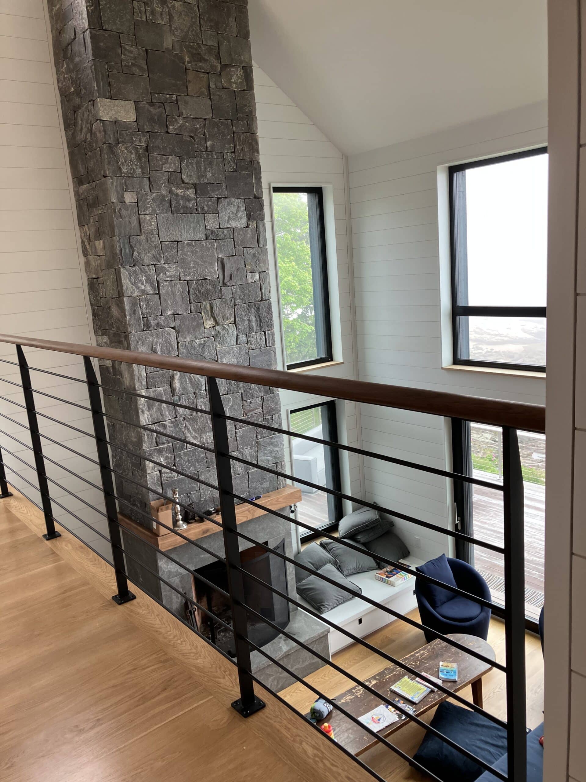 Stone fireplace viewed from the second floor balcony in the custom Bensonwood house on the coast of Maine